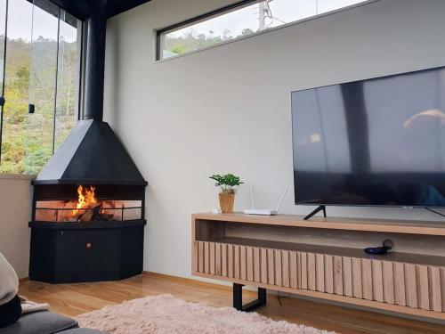 ein Wohnzimmer mit einem großen TV und einem Kamin in der Unterkunft Lux 28 - Casa moderna piscina aquecida e vista in Teresópolis