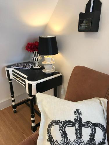 a side table with a lamp and a table with a pillow at Alice in Wonderland cottage by the sea in Torquay
