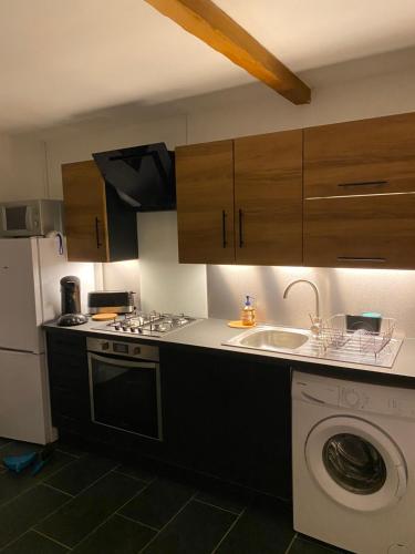 une cuisine avec une machine à laver et un évier dans l'établissement Le chant des Cigales, à La Celle-sous-Gouzon