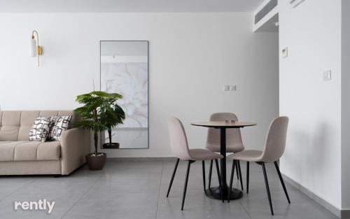 a living room with a table and chairs and a couch at Luxury Apartments And Studios At Sea Side By Rently in Eilat