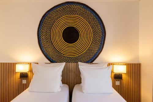 two beds in a room with a painting on the wall at Hôtel Korner Châtelet in Paris