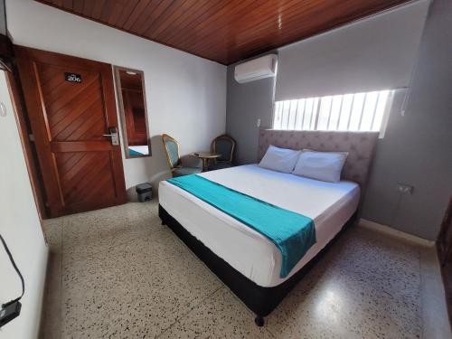 a small bedroom with a bed and a wooden door at Hotel Med Suites 94 in Barranquilla