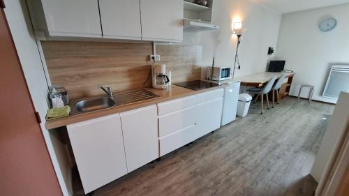 une cuisine avec des armoires blanches et un plancher en bois dans l'établissement Résidence Aquatis, à Chasseneuil-du-Poitou