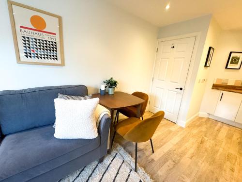 a living room with a blue couch and a wooden table at Stylish apartment 1 min to town centre and harbour in Lymington
