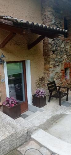 a stone building with two flower boxes and a bench at Albaluna 2 casa vacanza in Dronero