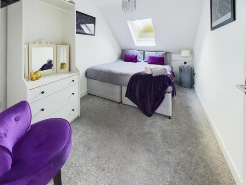 a bedroom with a bed and a mirror and purple chairs at A beautiful apartment near all amenities in Ottery Saint Mary