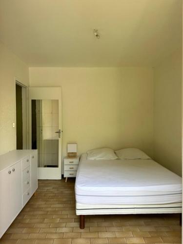 une chambre avec un lit blanc et une salle de bain dans l'établissement Appartement proche plage, à La Londe-les-Maures