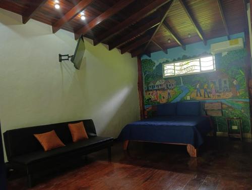 a room with a bed and a couch and a mural at Villas Kiki in Puerto Viejo