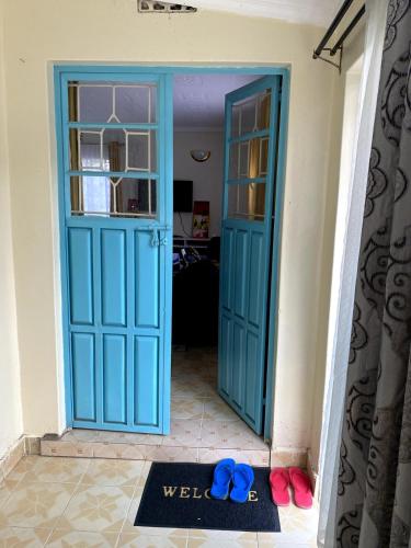 a blue door with a welcome mat in front at Matildah's Tranquil Haven in Siaya