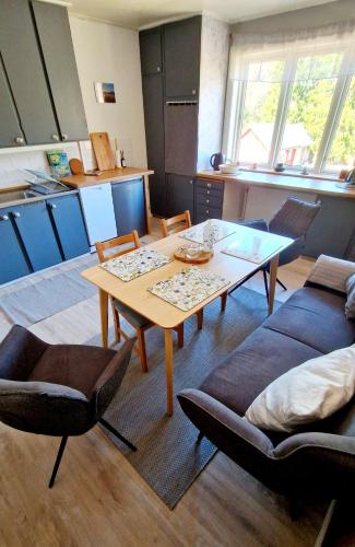 a living room with a table and chairs and a kitchen at Stationshuset Dalarna Apartments in Sörsjön