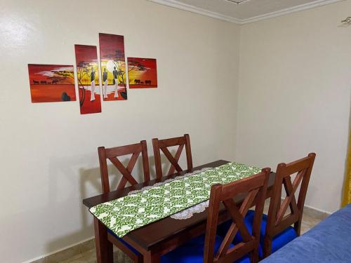 a dining room table with two chairs and paintings on the wall at Matildah's Tranquil Haven in Siaya