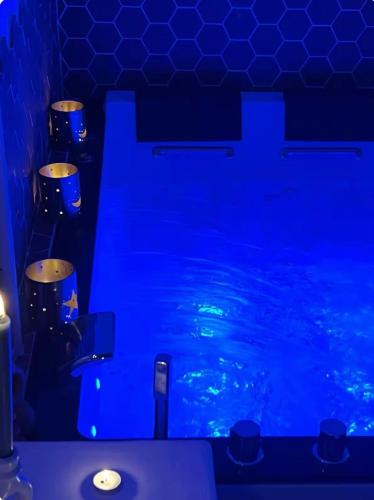 La salle de bains est pourvue d'une piscine avec des lumières bleues. dans l'établissement Instant Douceur Suite Jacuzzi, à Saintry-sur-Seine