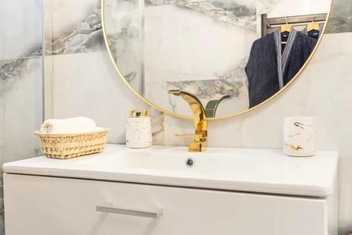 La salle de bains est pourvue d'un lavabo avec un robinet en or et un miroir. dans l'établissement Instant Douceur Suite Jacuzzi, à Saintry-sur-Seine