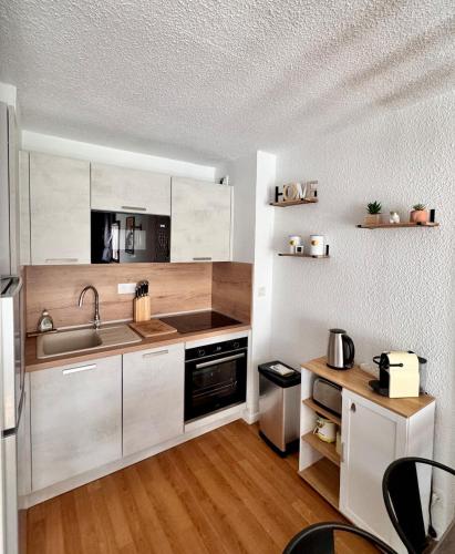 une cuisine avec des armoires blanches et un évier dans l'établissement Ski, confort famille, appartement Cosy, Vue montagne,piscine,parking, à Bagnères-de-Bigorre