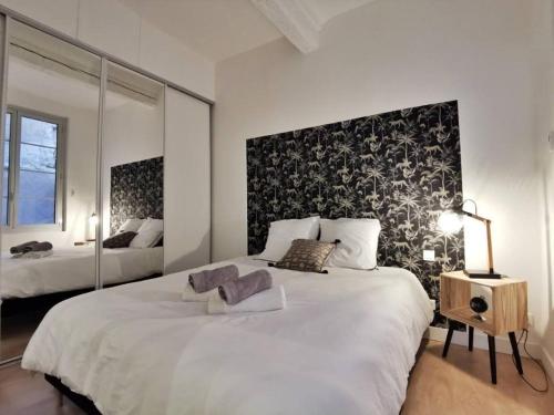 une chambre avec un grand lit blanc avec un mur d'accent noir dans l'établissement L'Aixcapade, à Aix-en-Provence