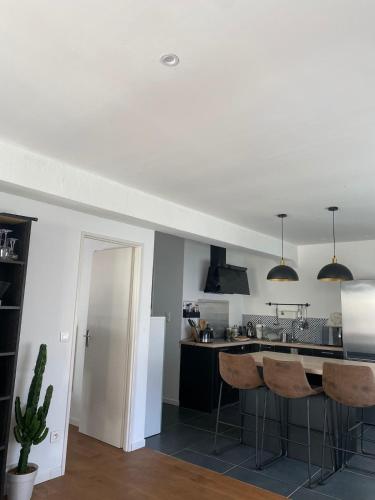 une cuisine avec des murs blancs et un comptoir avec des tabourets dans l'établissement Confort & tranquillité à deux pas des restos et de la gare, à Perpignan