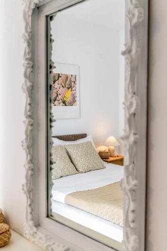 a mirror reflecting a bed in a bedroom at Litsa Malli Rooms in Pollonia