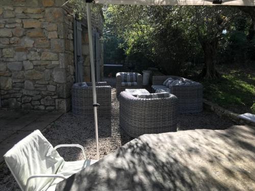 un groupe de tables et de chaises en osier sous un parasol dans l'établissement Charmante maison, à Fayence