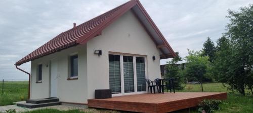 a small white house with a wooden deck at Poza Zasięgiem in Janów Podlaski