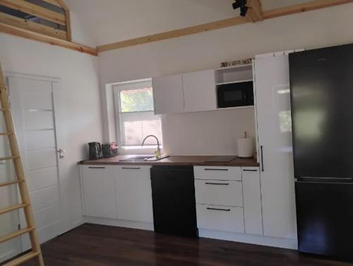 a kitchen with white cabinets and a black refrigerator at Poza Zasięgiem in Janów Podlaski