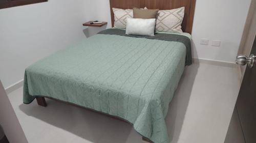 a bed with a green comforter in a room at New Oceanfront Apartment in Mazatlán