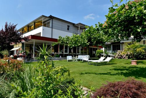 a building with a yard with white furniture in front of it at Strandhaus Eberle in Immenstaad am Bodensee