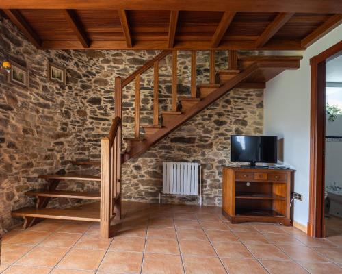 a living room with a staircase and a tv at Casa 1 LarSanAdrian in Coristanco