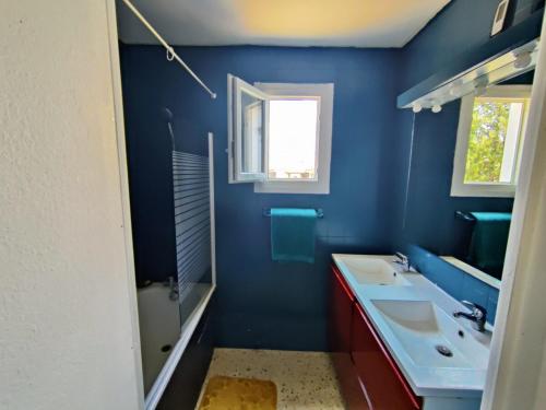 a blue bathroom with two sinks and a mirror at Maison Climatisée pour vous seul avec piscine et jardin in Caux