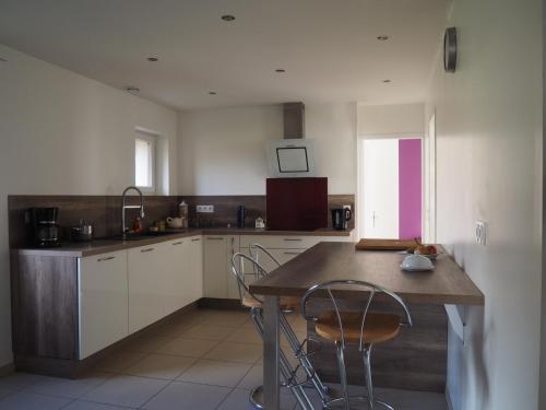 une cuisine avec des armoires blanches et une table et des chaises en bois dans l'établissement La Picane, à Gagnac-sur-Cère