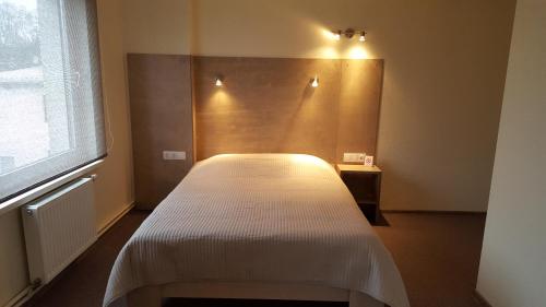 a bedroom with a white bed in a room with a window at Hotel Gulbene in Gulbene