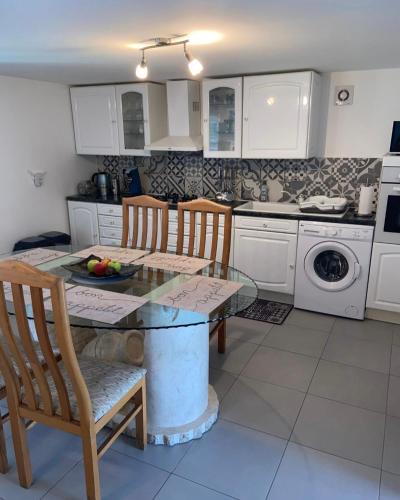 une cuisine avec une table et des chaises en verre et une cuisine avec un lave-vaisselle dans l'établissement La jarre du médoc, à Pauillac