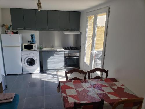 a kitchen with a table and a white refrigerator at Les lavandins d'ASMA in Bollène