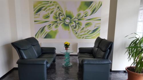 two chairs and a table in a room with a painting at Hotel Gulbene in Gulbene