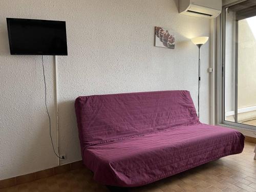 Cette chambre comprend un lit violet et une télévision. dans l'établissement Studio Héliopolis AB 310 - 3 personnes, au Cap d'Agde