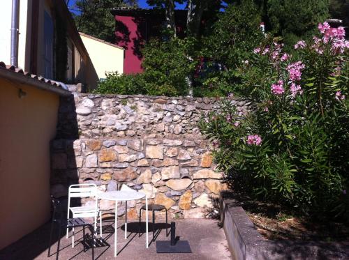 a stone wall with two chairs and a table in front of it at Maisonnette dans un parc du 18ème in Aix-en-Provence