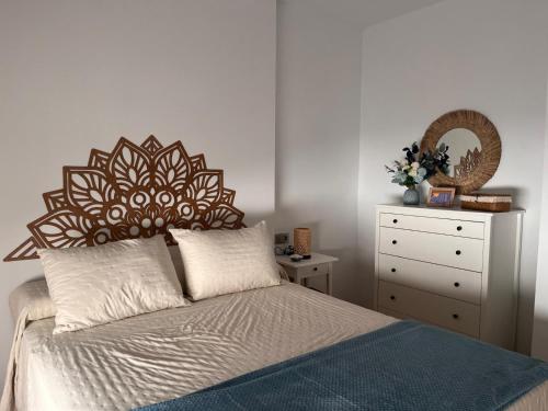 a bedroom with a bed with a wooden headboard and a dresser at Recidencial Cruz del Mar "Duplex Villa Amanecer" in Chipiona