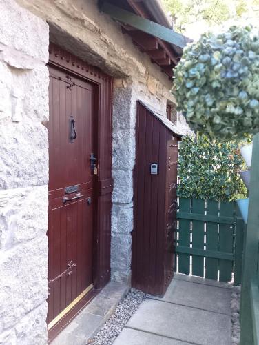two wooden doors on a stone building with a gate at Smiddy House in Spean Bridge