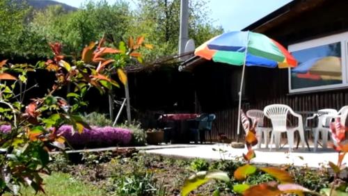 a patio with a colorful umbrella in a yard at Vikendica Mia Balkana in Mrkonjić Grad