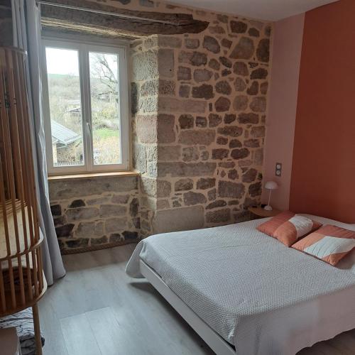 une chambre avec un lit et un mur en pierre dans l'établissement Le Crochet de Pervenche, à Recoules-Prévinquières