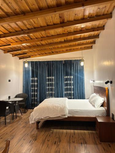 a bedroom with a bed and a wooden ceiling at Charlie's Little Palace in Mukteshwar