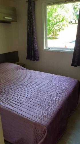 - une chambre avec un lit violet en face d'une fenêtre dans l'établissement Mobil-home 3 chambres 6 personnes au camping de bairon 08390, à Le Chesne