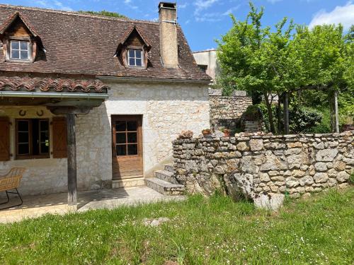 an old stone house with a stone wall at La Bergerie d'Olivier in Saint-Cirq-Lapopie