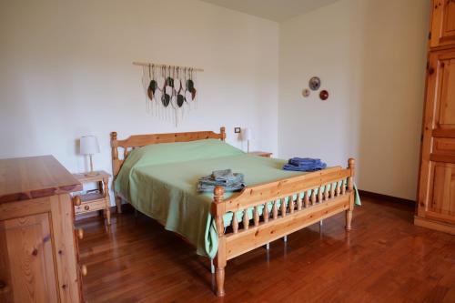 a bedroom with a wooden bed with a green bedspread at B&b Ponte Pietra in Massazza