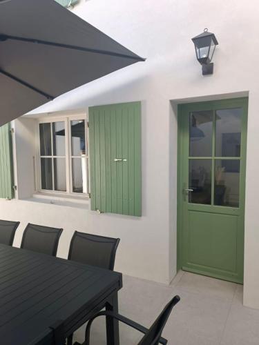 une maison avec une porte verte, une table et des chaises dans l'établissement Maison de centre-ville Ars en Ré, à Ars-en-Ré