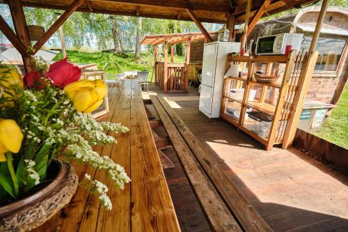 a porch with a wooden table with flowers and a refrigerator at Kempings Daugmales in Landzāni