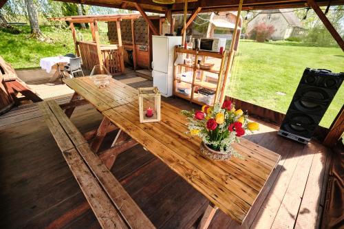 a wooden table with a vase of flowers on a porch at Kempings Daugmales in Landzāni