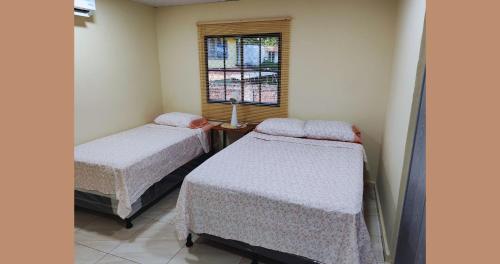 Dos camas en una habitación con ventana. en Suite Nantli, en Antiguo Cuscatlán