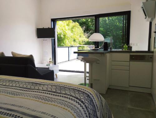 un salon avec une cuisine et une grande fenêtre dans l'établissement Cozy studio house with terrace 15 min from Paris, à Bièvres