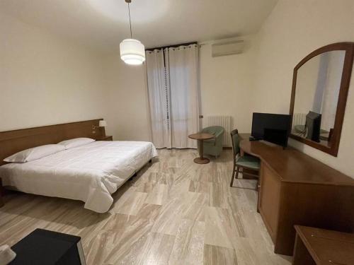 a bedroom with a bed and a desk and a mirror at Hotel Clementi in Salice Terme