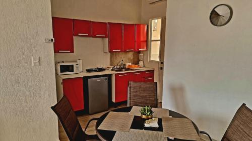 a kitchen with red cabinets and a table and chairs at Apartmento nuevo con alberca, Cancun in Cancún